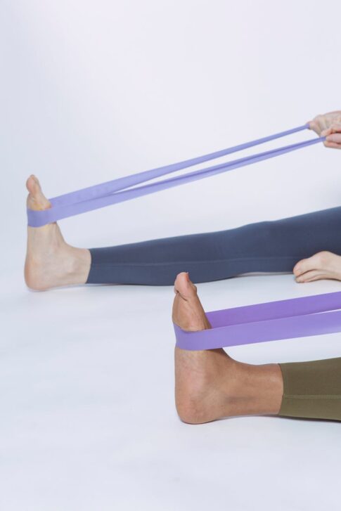crop people exercising with elastic purple loops